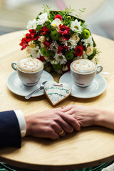 couple drinks coffee with ginger cookie in form of a heart at a cafe