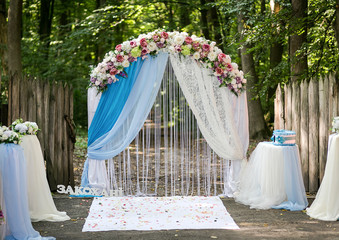 arch decorated with pink and white flowers standing in the woods