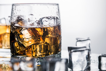 whiskey in a glass with ice on a light background in the contour light. Alcoholic beverages