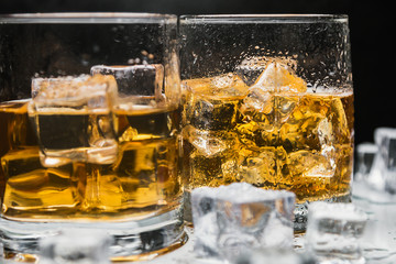 whiskey in a glass of ice on a black background. Alcoholic beverages