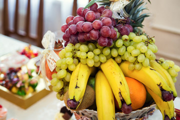 fruit on a plate such as bananas and grapes, kiwi, orange