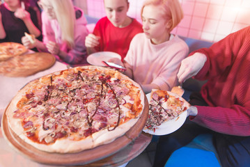 Great appetizing pizza on the background of a group of friends in a cozy pizzeria. Lunch with...