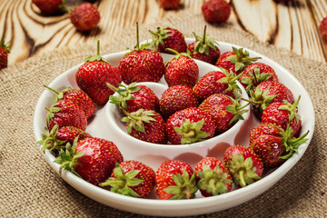 red strawberries in bowl on a wooden background