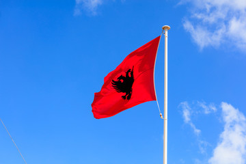 Albania flag. Albanian flag on a pole waving on blue sky background