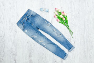 Blue ragged jeans and bouquet of tulips. Fashionable concept