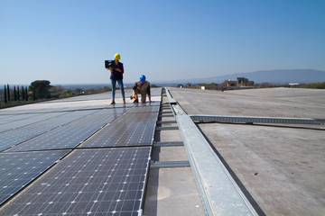 young engineer girl and an elderly skilled worker fitting a photovoltaic plant