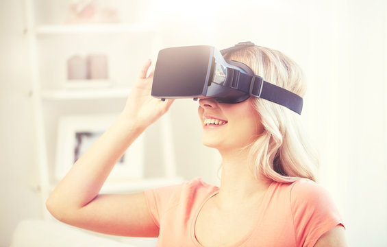 technology, virtual reality, cyberspace, entertainment and people concept - happy young woman with virtual reality headset or 3d glasses at home