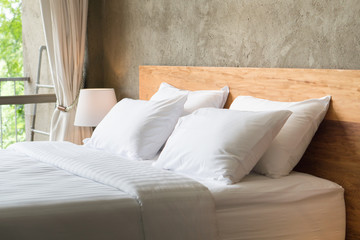 White pillows on the bed in loft style bedroom. - obrazy, fototapety, plakaty