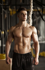 Fototapeta premium Sporty man with a rope. Photo of young man with perfect body after training. Strength and motivation