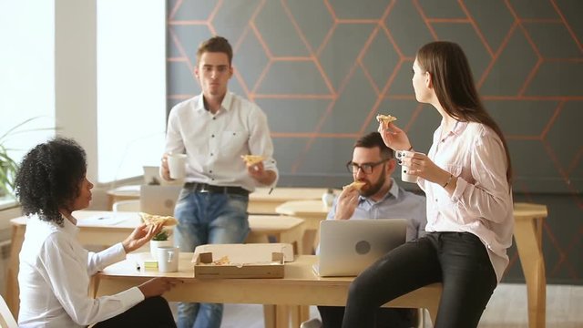 Business team of young people enjoying eating pizza together, millennials group talking having fun sharing lunch in cozy office, good relationships at work, food delivery service and catering