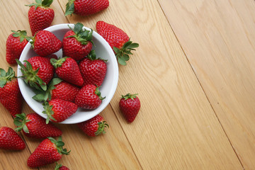 Fresh strawberries in a bowl on wooden background