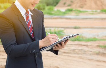 Businessman surveying land for industrial project.Selective focus at hand.