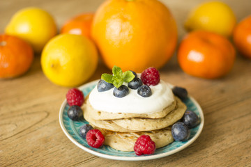 Homemade pancakes with fruits and fresh oranges and lemons on the background