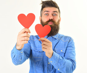 Young man with beard in denim shirt holding paper hearts