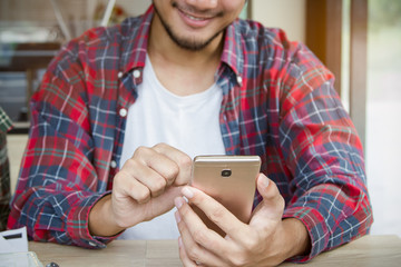 Happy young male using mobile phone and smiling in coffee shop.