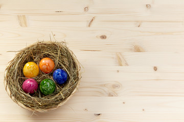 Korb mit Heu und bunten Eiern auf Holz aus Fichte