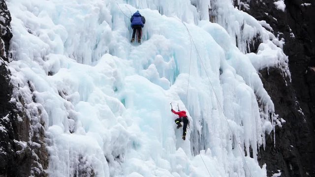 Climber breaks off glacier and hangs on belay rope and ice axes