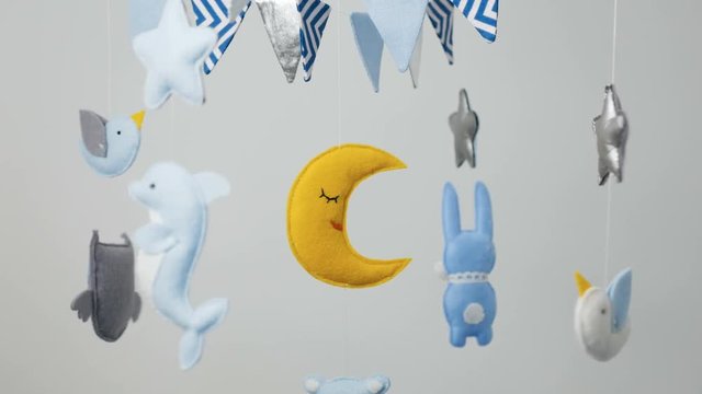 baby mobile with blue hand-stitched animal and bird toys with yellow moon on white wall background