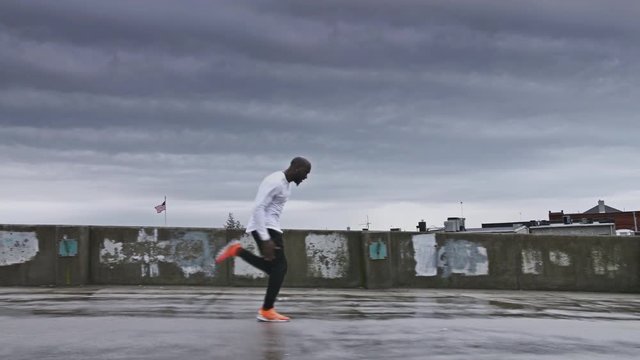 4K Man sprinting on wet concrete