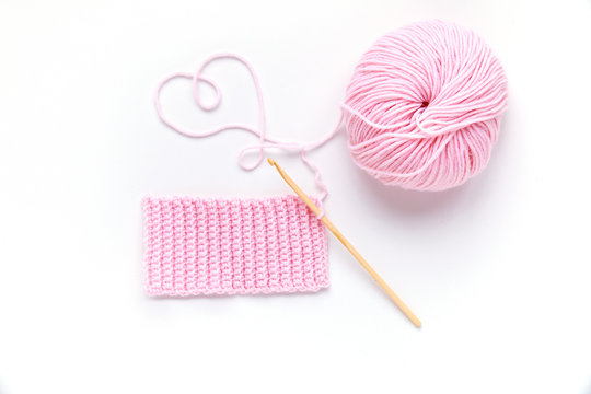 Pink ball of yarn with wooden crochet hook.