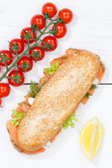 Sandwich Baguette Vollkorn Brötchen belegt mit Lachs Fisch Hochformat von oben auf Holzbrett