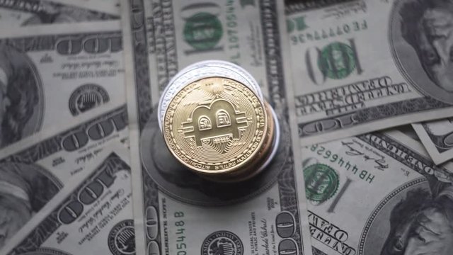 Gold Bitcoin on a top of othe coins rotating on bills of 100 dollars. Worldwide virtual internet cryptocurrency and digital payment system. Digital coin money crypto currency on bitcoin farm.