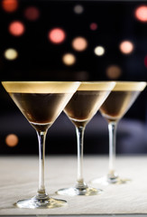 Drei Cocktails in braun und weiß in einer Reihe vor dunklem Hintergrund