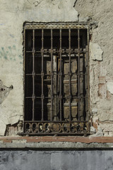 Fototapeta na wymiar Vieja venta con reja una vieja ventana con un reja oxidada en un muro desconchado de un edificio en Madrid. España