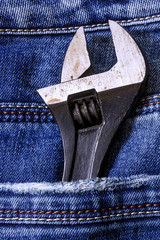 Adjustable wrench in the back pocket of denim jeans