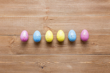 Happy easter eggs on color for holiday on wooden background top view flat lay