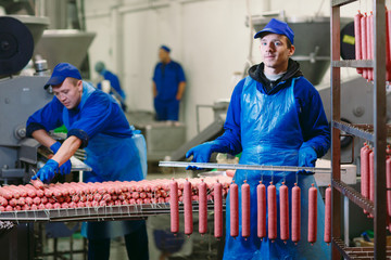 Portrait of butchers processing sausages at meat factory