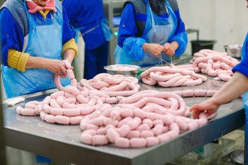 Butchers processing sausages at meat factory.