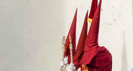 Three penitents waiting for the entrance to the temple on Holy Friday in Huelva, Spain
