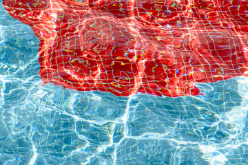 Texture of water in swimmingpool and reflections in blue and red