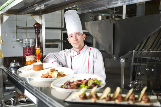 Portrait of a chef with cooked food in the Kitchen in the restaurant.