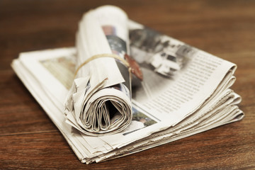 Bunch of folded newspapers on wooden table. Fresh morning papers with news, side view, selective focus