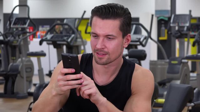 A young fit man takes selfies in a gym - closeup