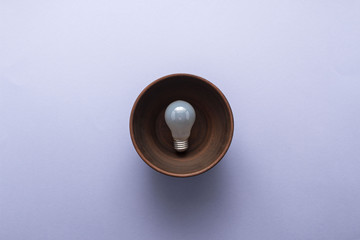 Creative idea - light bulb in brown plate on pastel purple background