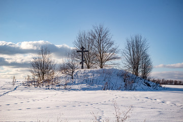 Barrow with an Orthodox cross in the middle of the snow-covered field