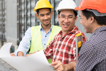 Fototapeta premium Engineer, contractor, architect teamwork. Group of happy builder construction people talking and planning work schedule holding blueprint in manager hands.