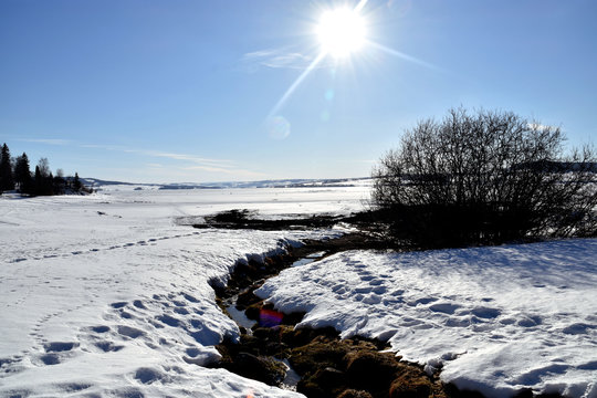 The sun shines over the frozen lake