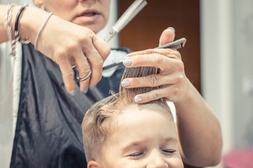 Obraz na płótnie Canvas Small kid during haircut at barber shop.