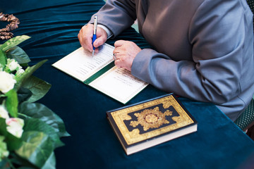 Old mullah registers Muslim marriage Nikah. Islamic customs. Quran and rrayer beads on a dark blue velvet background.