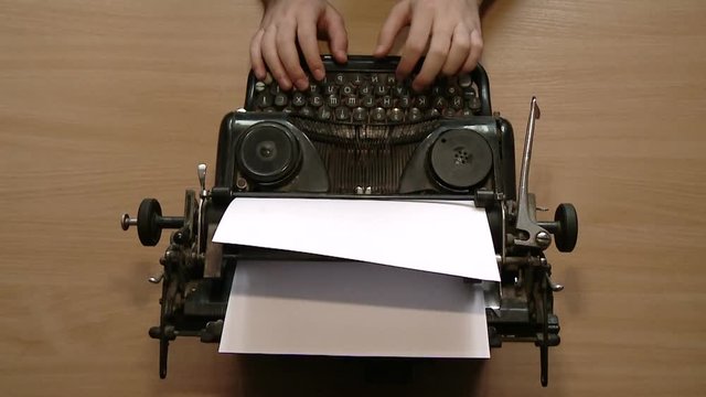 Writer typing with retro writing machine. View from above.