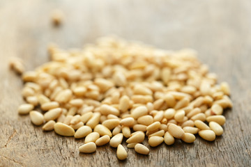 A pile of crumbled peeled pine nuts on an old brown wooden table