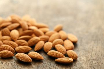 Pile of almonds on an old brown wooden table, copy space