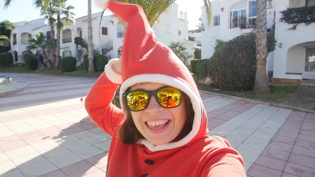 Happy young woman in santa hat taking selfie