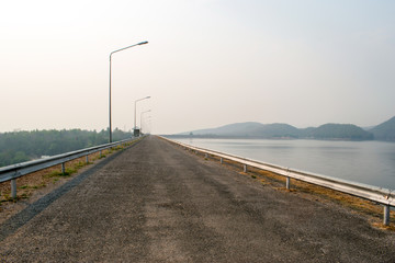 The  road on the edge of the dam, which has a nature background.