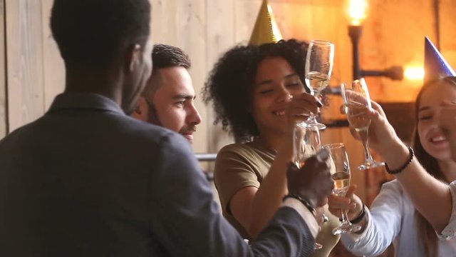 Multi-ethnic students enjoying celebration, diverse young african american and caucasian friends hanging out drinking champagne dancing together, colleagues having fun entertaining at staff party
