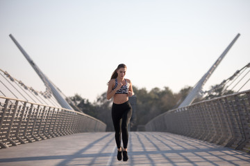 Active woman runner jogging across bridge, outdoors running, sport and healthy lifestyle concept.